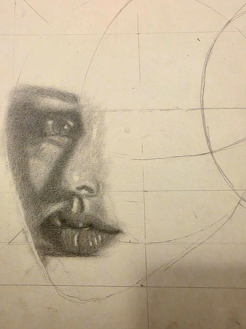 Drawing in progress on cream paper. One eye, the nose and the lips are shaded in graphite, surrounded by construction lines and a pencil grid.
